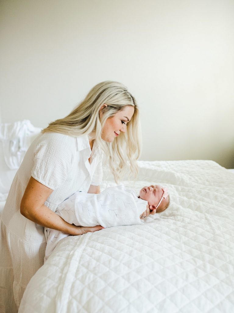 natural light in-home newborn session mom with baby in all white room in a swaddle
