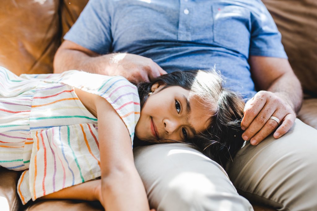 daughter cuddling with her dad at their in-home photos
