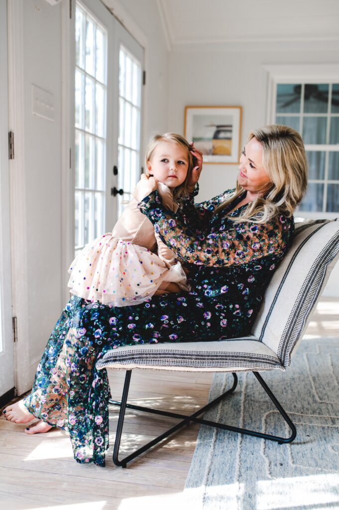 Mom wears a beautiful sequin dress while her daughter wears a tutu and sits in her lap.