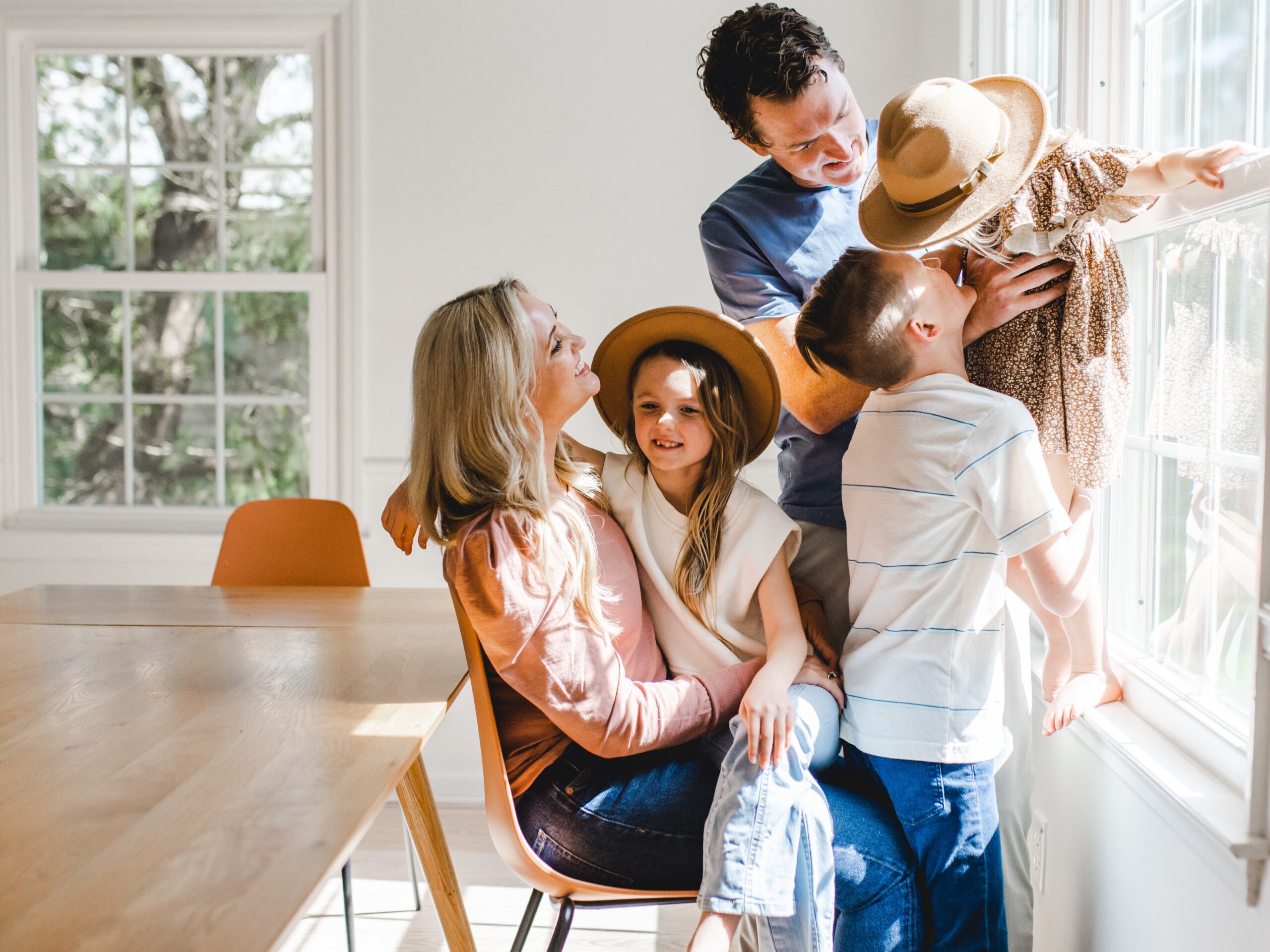 family playing with hats while the sun lights up the kitchen