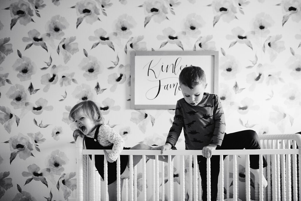 Two small children try to escape from their crib in this black and white image from a personal project.